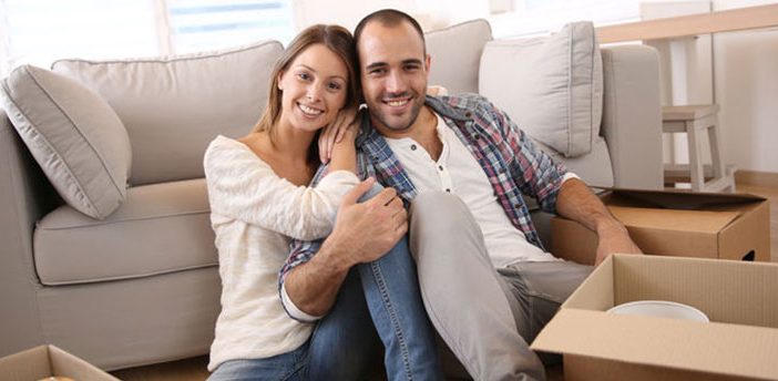 Young couple sitting on floor with moving boxes
