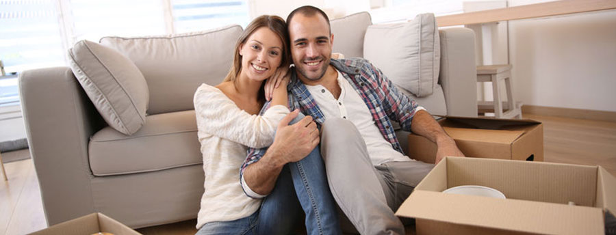 Young couple sitting on floor with moving boxes