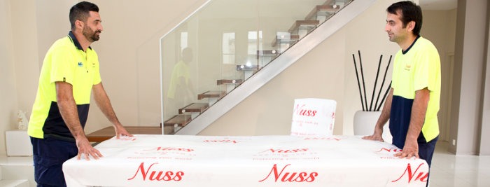 Nuss Removals staff moving table wrapped in Nuss Removals foam wrap