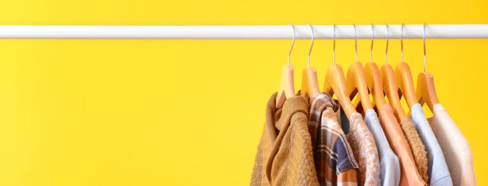 Rack with hanging clothes on color background